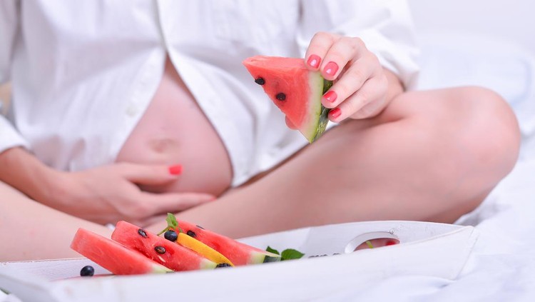 Pregnancy and nutrition - pregnant woman with a bowl of fruit and vegetables .