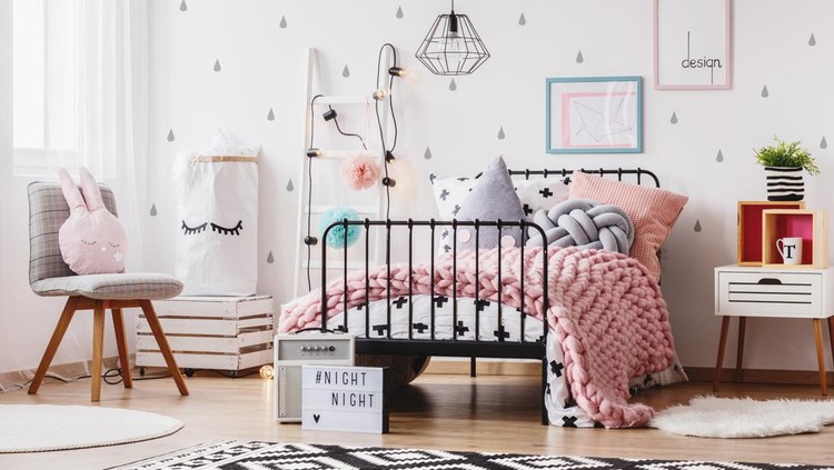 kamar anak Pink knit blanket on girl's bed with pillows in colorful bedroom with ladder, chair and plant