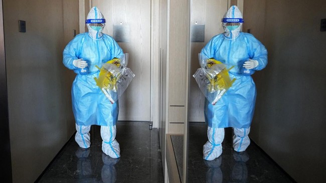Bartender di resor ski kota Zhangjiakou, China menggunakan baju hazmat biru dan putih sembari menuangkan koktail di area Olimpiade Musim Dingin Beijing.