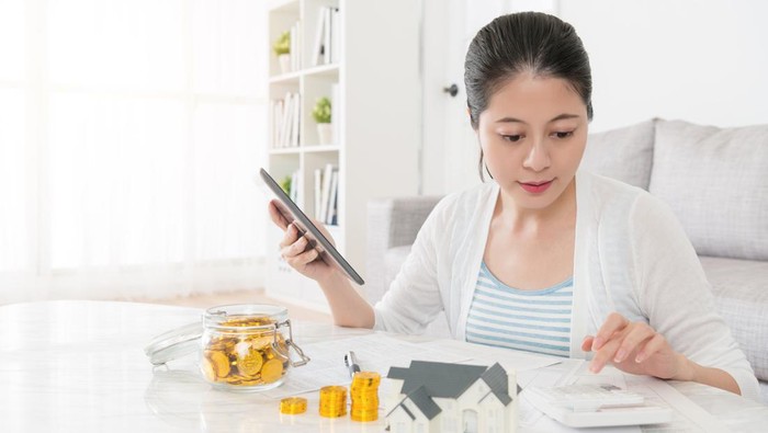 elegant beauty girl using calculator counting personal deposit when she choosing new house building through online information with mobile pad computer.