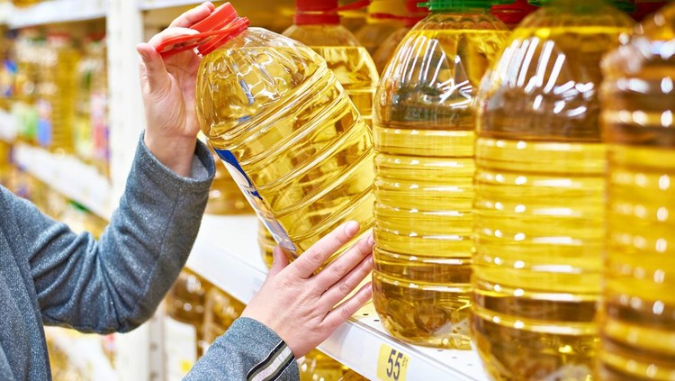 Big plastic bottle of olive oil in the hand of the buyer at the grocery store