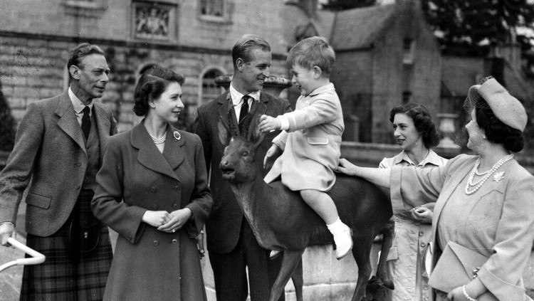 Kisah 70 Tahun Ratu Elizabeth Memimpin Kerajaan Inggris FILE - Britain's Prince Charles, watched by, from left, King George VI, Princess Elizabeth, Prince Philip, Princess Margaret and Queen Elizabeth, sits on a sculpture of a deer in the grounds of Balmoral Castle, Scotland, Aug. 1951. Queen Elizabeth II will mark 70 years on the throne Sunday, Feb. 6, 2022, an unprecedented reign that has made her a symbol of stability as the United Kingdom navigated an age of uncertainty. (AP Photo, File)
