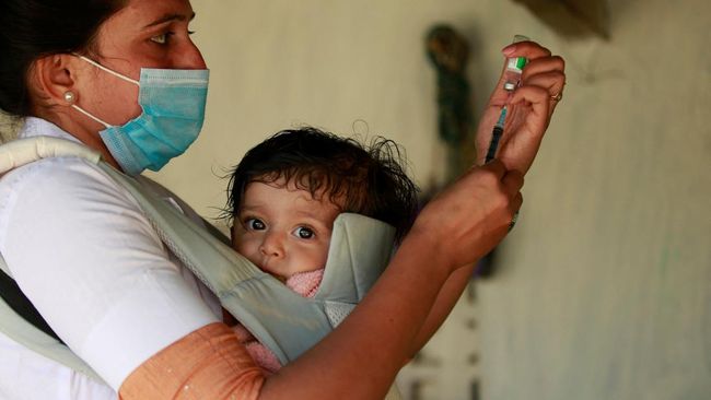 FOTO: Perjuangan Melayani Vaksinasi Sambil Gendong Bayi