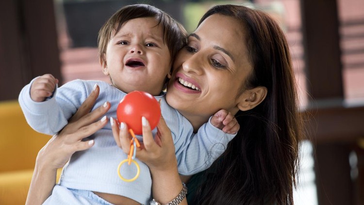 1183297707 Mother trying to console crying baby boy at home