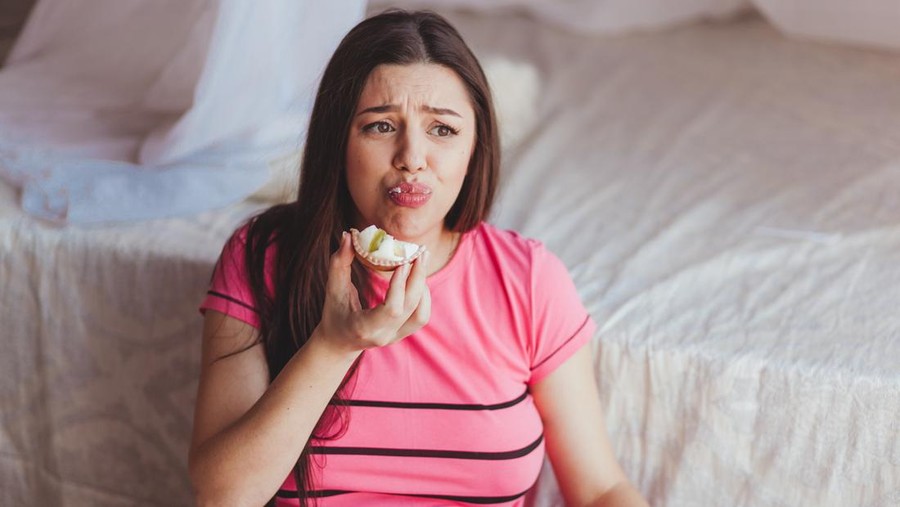 Young disgust female after trying piece of cake, healthy diet concept, pregnancy food.