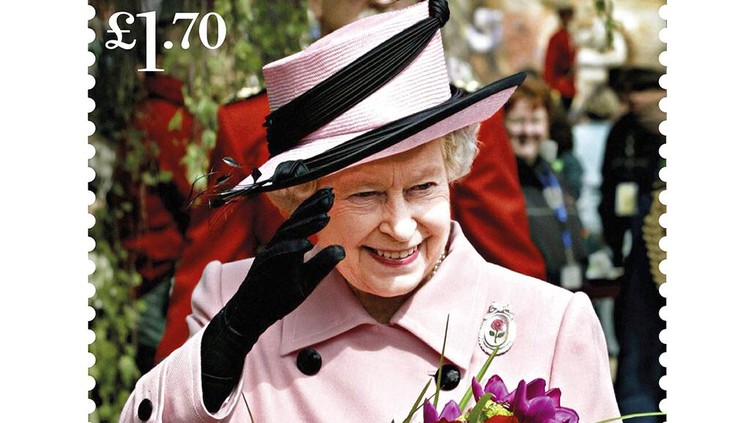 This undated handout provided by Royal Mail on Friday, Feb. 4, 2022 shows of one of eight new stamps showing Queen Elizabeth II smiling, wearing a burgundy outfit and hat, during a visit to the MI5 headquarters in February 2020, which has been issued to mark the monarch's Platinum Jubilee. (Royal Mail via AP)