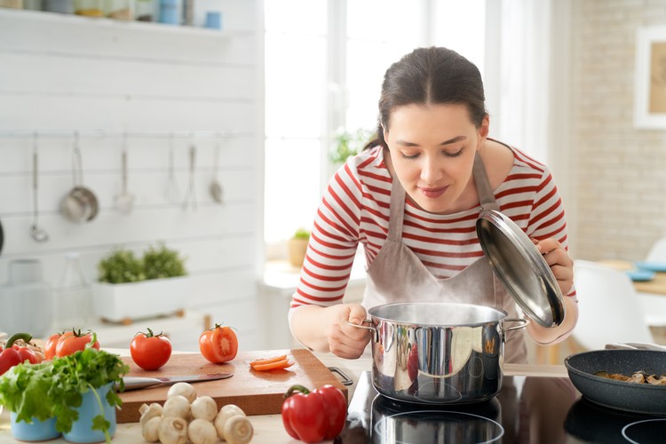 Healthy food at home. Happy woman is preparing the proper meal in the kitchen.