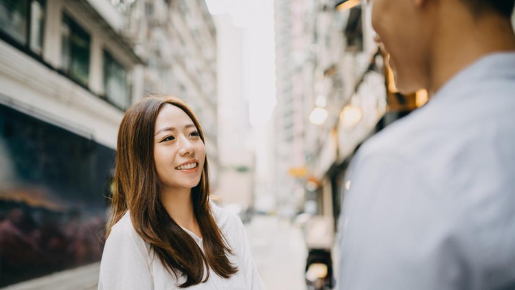 Smiling young couple talking on city street in Hong Kong