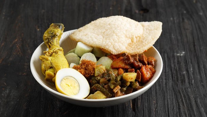 Lontong Cap Go Meh. Indonesia Peranakan Dish of Rice Cake Soup or Lontong Sayur with Opor Ayam Chicken Curry, Spicy Chayote Curry, SAmbel Goreng Ati Kentang, and Egg. Served with Shrimp Cracker
