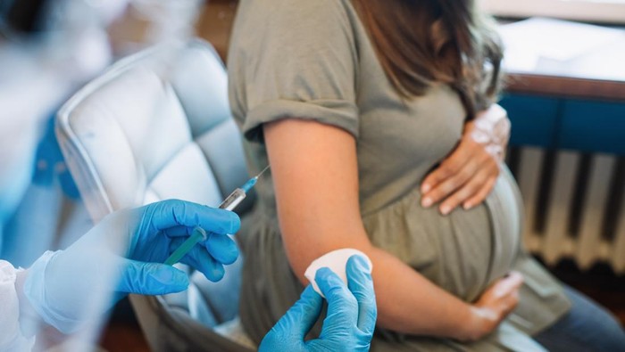 Pregnant woman getting vaccine at home. COVID-19 vaccination concept.