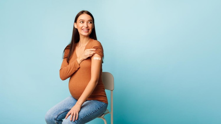 ibu hamil divaksin I Got Vaccinated. Happy Pregnant Woman Showing Arm With Medical Bandage After Vaccine Injection Shot Against Covid-19 On Blue Background. Antiviral Immunization And Pregnancy. Panorama, Copy Space