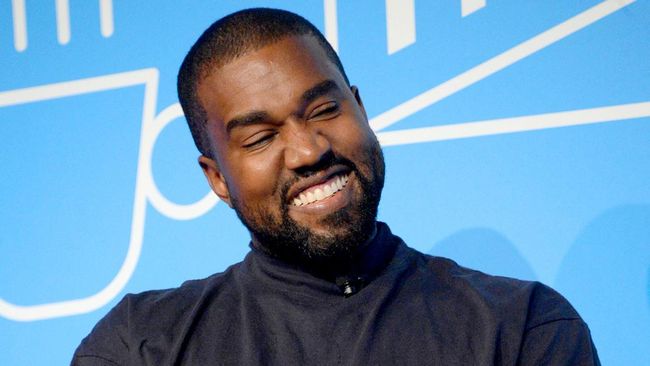 Kanye West tampil dengan sandal jepit bling-bling dengan tali putih dan embelishment di atasnya dalam show Burberry.