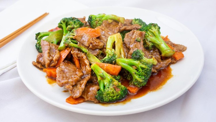 A view of a Chinese plate of beef and broccoli, in a restaurant or kitchen setting.
