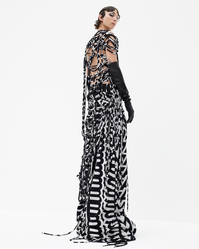 Gaun berhiaskan motif grafis logo yang dibuat dalam konstruksi fringes, menghasilkan kreasi busana yang edgy sekaligus seksi. Foto: courtesy of Marc Jacobs