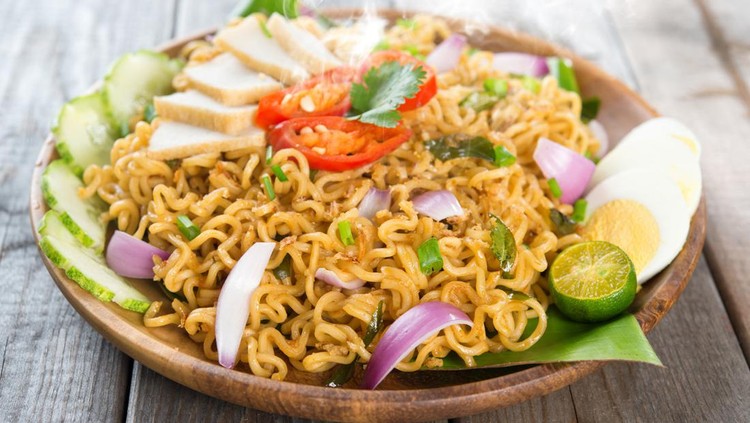 Malaysian style maggi goreng mamak  or spicy fried curry instant noodles.  Asian cuisine, ready to serve on wooden dining table setting. Fresh hot with steamed smoke.