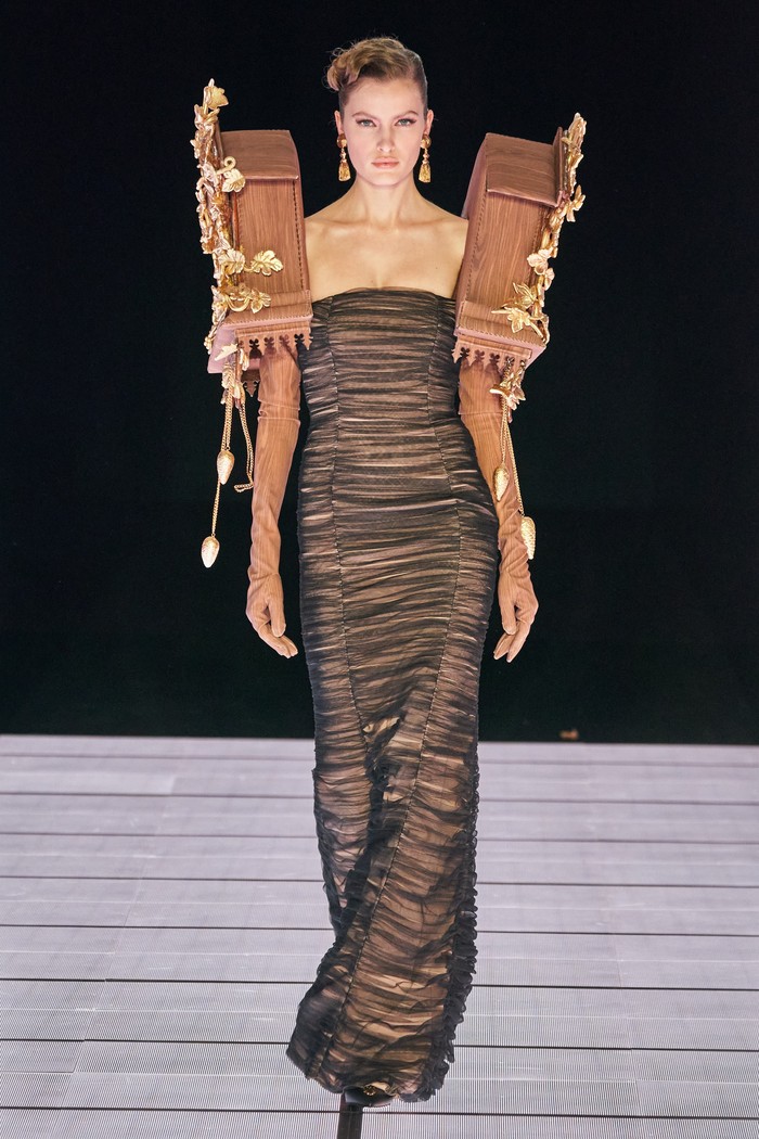 Selanjutnya, dua jam dinding masuk dalam koleksi Moschino. Gaun strapless semakin mencolok dengan ornamen dua cuckoo clock di pundak. Foto: vogue.com