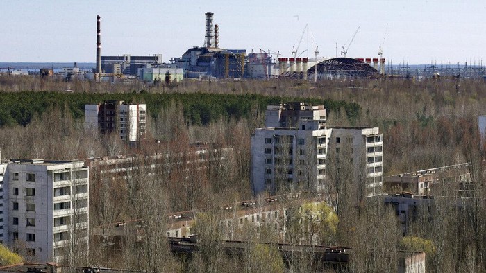 The town of Prypyat is seen against the background of the damaged reactor at the Chernobyl nuclear power plant in Prypyat, Ukraine, Tuesday, April 23, 2013. At background right is a gigantic steel-arch under construction to cover the remnants of the exploded reactor. Ukraine marks the 27th anniversary of the world's worst nuclear disaster on April 26. (AP Photo/Efrem Lukatsky)