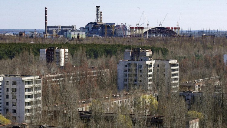 The town of Prypyat is seen against the background of the damaged reactor at the Chernobyl nuclear power plant in Prypyat, Ukraine, Tuesday, April 23, 2013. At background right is a gigantic steel-arch under construction to cover the remnants of the exploded reactor. Ukraine marks the 27th anniversary of the world's worst nuclear disaster on April 26. (AP Photo/Efrem Lukatsky)