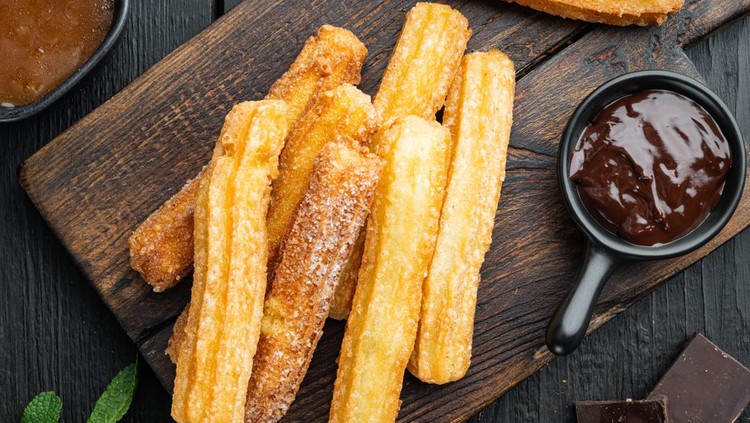 Churros with chocolate, Traditional Spanish cusine, on black wooden table background, top view flat lay