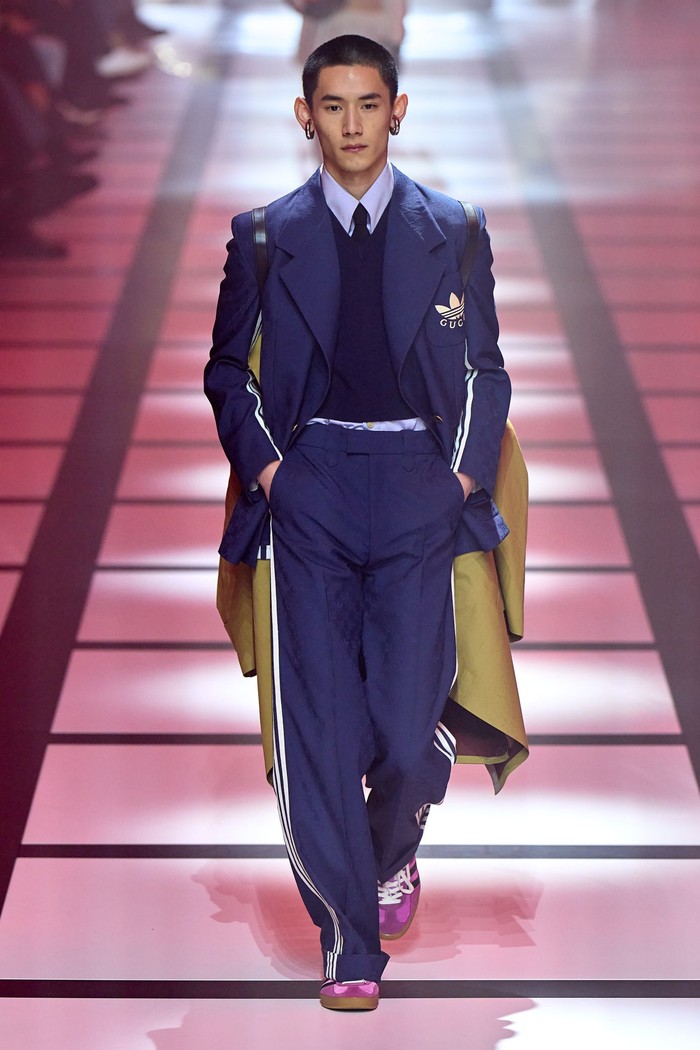 Pada koleksi busana pria, Alessandro Michele selaku desainer Gucci menampilkan ragam kreasi setelan jas berhiaskan logo garis Adidas.Foto: Filippo Fior/GoRunway/Vogue