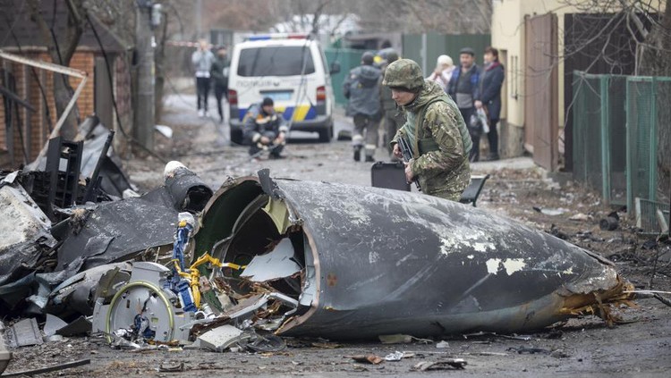 A Ukrainian Army soldier inspects fragments of a downed aircraft in Kyiv, Ukraine, Friday, Feb. 25, 2022. It was unclear what aircraft crashed and what brought it down amid the Russian invasion in Ukraine. Russia is pressing its invasion of Ukraine to the outskirts of the capital after unleashing airstrikes on cities and military bases and sending in troops and tanks from three sides. (AP Photo/Vadim Zamirovsky)
