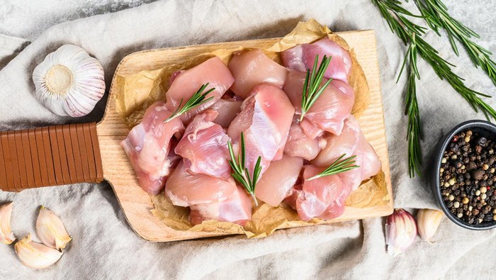 chicken thigh fillet cut into cubes. Gray background. Top view.