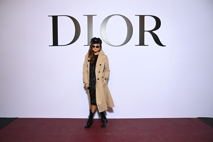Bintang serial Emily in Paris, Ashley Park tampil dalam padanan trench coat dan little black dress. Untuk memberi nuansa quirky, ia memakai cap dan sunglasses. Foto: Getty Images For Dior/Pascal Le Segretain
