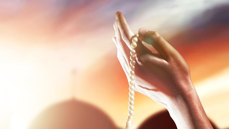Muslim man praying with prayer beads on his hands with dramatic sky background