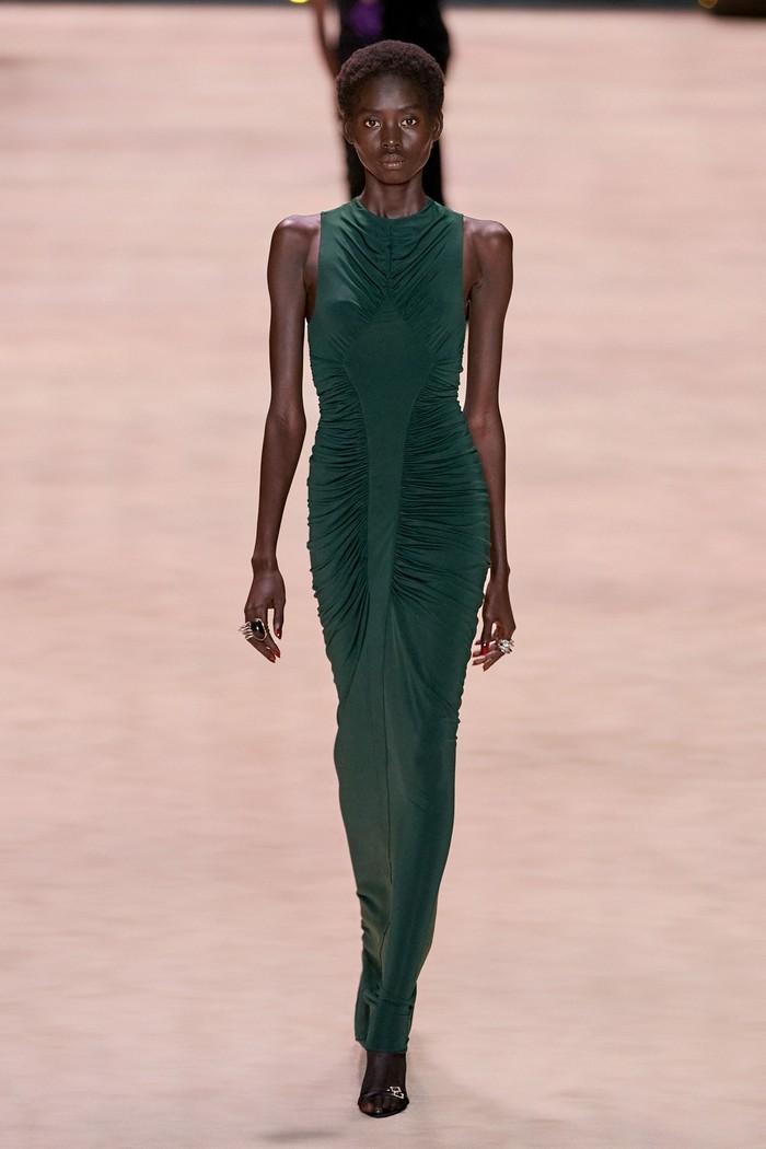 Selain gaun hitam, kehadiran gaun hijau detail kerutan memberi ide baru akan tampilan yang sophisticated. Dress ini sendiri terbilang versatile dan cocok untuk dipakai gaya di siang dan malam hari. Foto: Alessandro Lucioni/Go Runway/Vogue