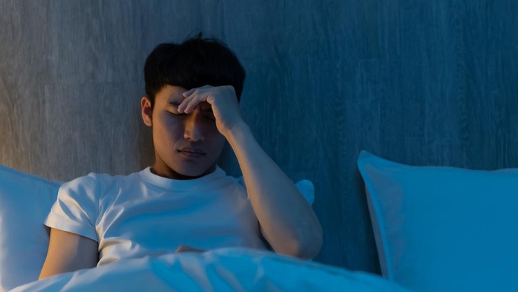 Ilustrasi Mata Sakit close up of asian young man is worrying about something on bed at night