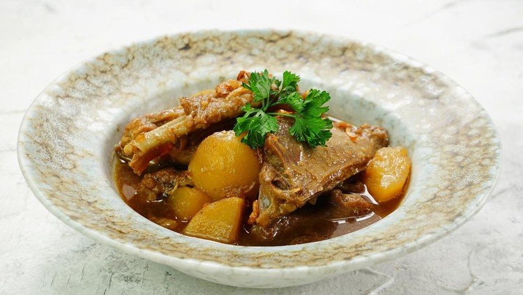 Close up look of Semur Ayam Kentang or Chicken and Potato Stew made with sweet soy sauce, spices and herbs. Popular home-cooked food in textured plate