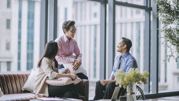 Indian male white collar worker in wheelchair discussion in office lounge with his colleague