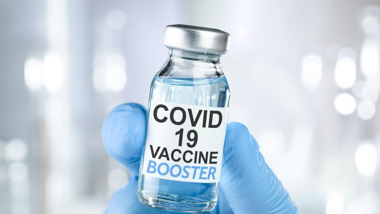 Hand in blue medical gloves holding a vaccine vial with Covid 19 Vaccine Booster text, for Coronavirus booster shot.