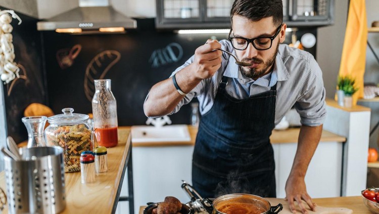 Photo of chef tasting delicious lunch he is preparing in the kitchen