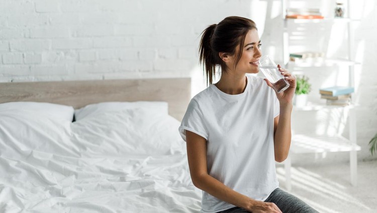 beautiful happy girl holding drinking water from glass in the morning