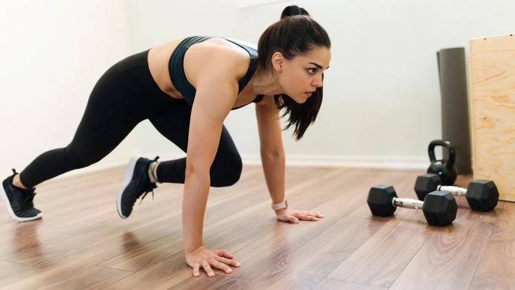 Olahraga mengecilkan perut Exercising at home with a high intensity interval training program. Fitness woman doing mountain climbers and cardio workout