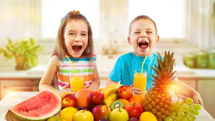 Happy children with fruits and fresh juice in kitchen, kids healthy eating concept
