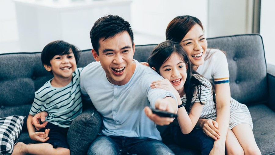 Cheerful asian family relaxing at home watching tv