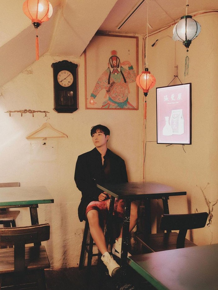 Masih dengan outfit berwarna hitam, Woo Do Hwan berpose dalam ruangan yang menonjolkan kota dengan cahaya neon sedikit redup, menambah kesan aesthetic yang tercipta./ Foto: Lee Jun Kyoung/Dazed Korea