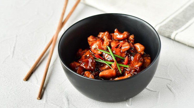 Chicken in teriyaki sauce, with green onion and chili pepper, in black plate, asian cuisine concept, chinese food, japanese food, thai cuisine. selective focus
