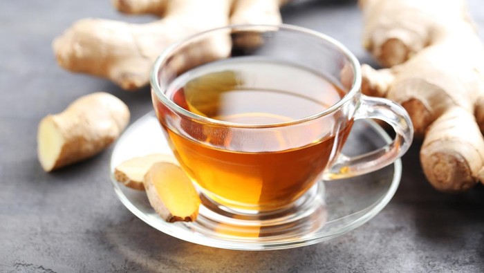 Cup of tea with ginger root on grey wooden table