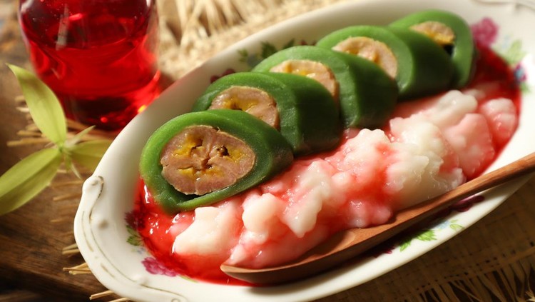 es pisang ijo Es Pisang Ijo, the popular dessert of plantain banana roll with coconut milk custard and red sugar syrup from Makassar (Ujung Pandang), South Sulawesi. The banana is wrapped with pandan crêpe; then served in slices on the custard. The dessert is plated on an vintage oval plate and placed on straw mat. An extra syrup in a small jug is placed next to the dessert.