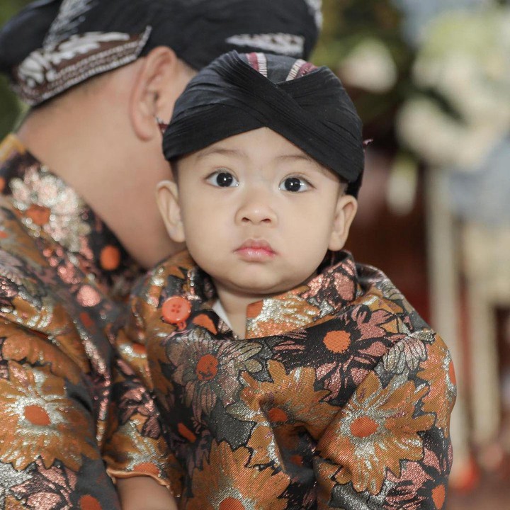 <p>Dalam acara ini, Baby R mengenakan pakaian senada dengan sang ayah, nih. Ia juga terlihat menggemaskan dengan adanya blangkon hitam di kepala. (Foto: Instagram: @tatajaneetaofficial)</p>