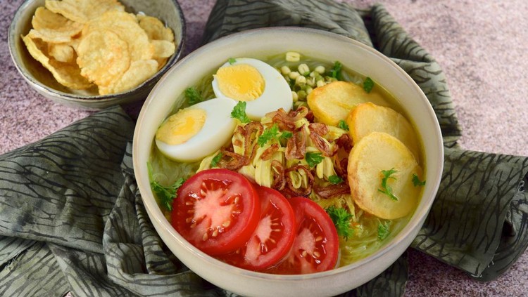 Soto Ayam, yellow turmeric chicken soup with vermicelli noodles, shredded chicken, boiled egg, fried potato, sprouts, tomato, parsley and fried shallots, served with Emping. Popular Indonesian food