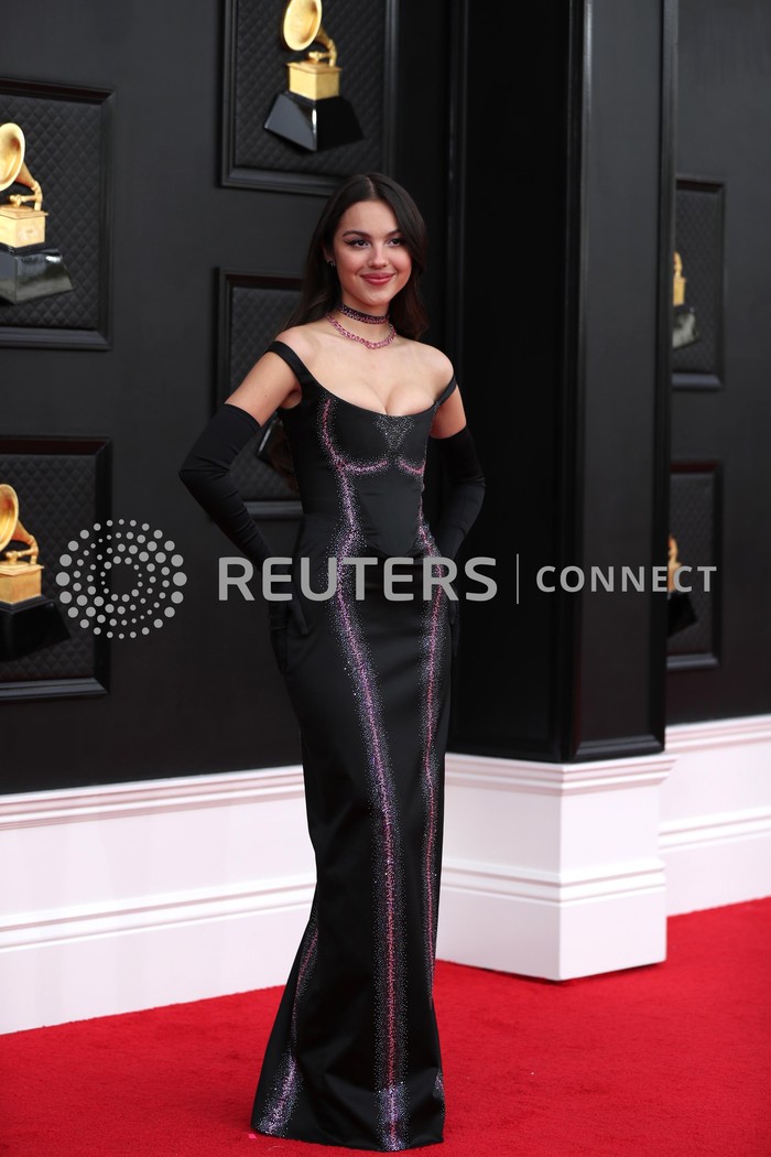 Sarung tangan panjang tampaknya jadi tren aksesori untuk red carpet belakangan ini. Gaun hitam yang edgy dapat terlihat lebih elegan seperti pada gaya Olivia Rodrigo dalam balutan Vivienne Westwood di Grammy Awards 2022. Foto: REUTERS/MARIA ALEJANDRA CARDONA