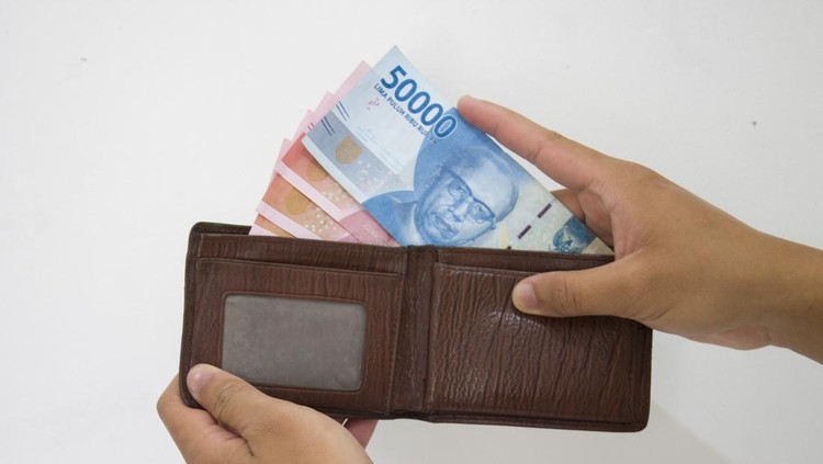 Ilustrasi Uang Hand holding Indonesian Rupiah (IDR) Red 100,000 bank notes currency from leather wallet on white background.