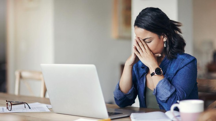 875247462 Shot of a young woman looking stressed while using a laptop to work from home
