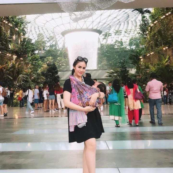 <p>Liburan ke Singapura, Momo Geisha tampaknya lebih nyaman menggunakan jarik untuk menggendong Si Kecil, ya Bunda. (Foto: Instagram @therealmomogeisha)</p>