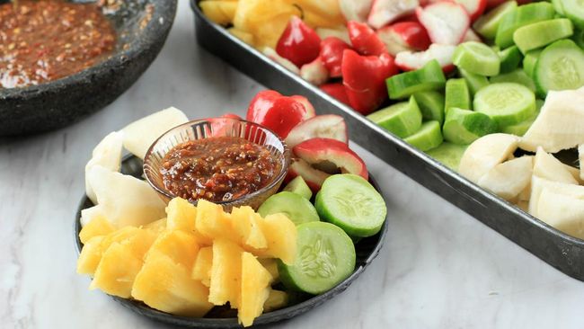 Rujak Cingur yang disajikan di piring tradisional, menampilkan kombinasi unik dari cingur sapi, tahu, dan sayuran segar dengan saus petis yang kental, menggambarkan kekayaan kuliner Jawa Timur