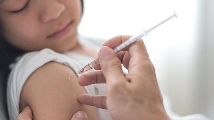 Young doctor giving COVID 19 vaccine to young woman at home